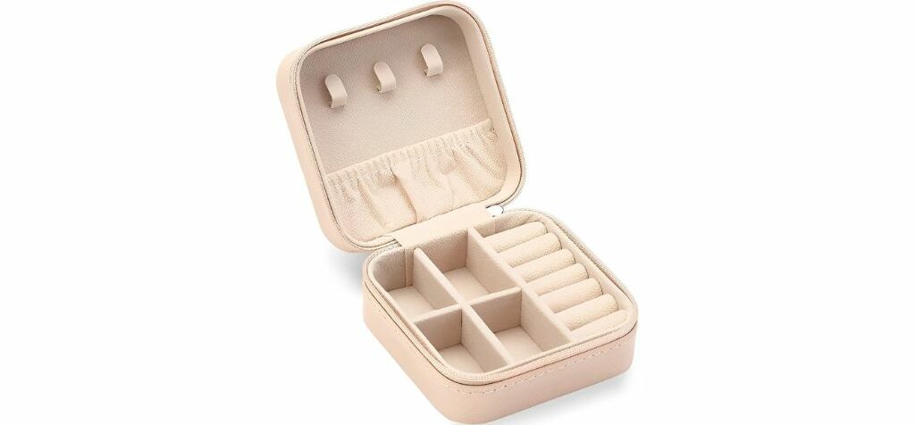 Beige small jewelry case with multiple compartments and ring holders inside.