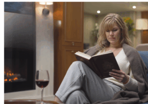 a woman in front of a fireplace reading a book on a yacht