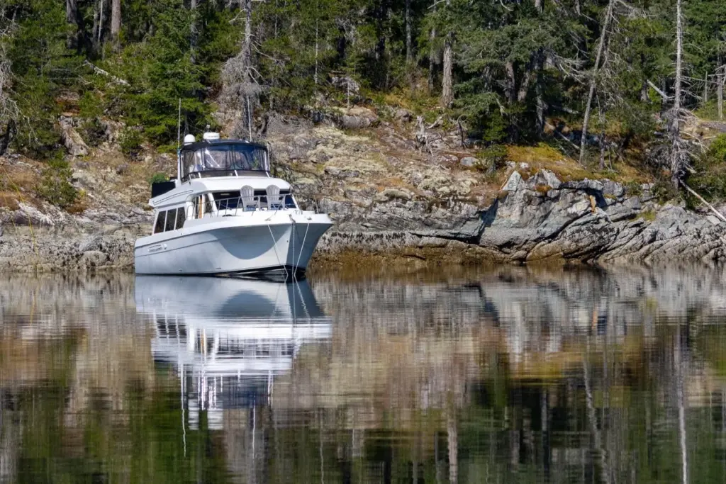 A white powerboat anchored in a quiet Pacific Northwest cove